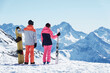 © Connect Images - Teenage boy snowboarder with sister skier looking out from snow covered mountain top, rear view,  Alpe-d'Huez, Rhone-Alpes, France