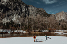 Friends Dragging Kayak Across Snow, Yosemite Village, California, United States