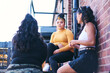 © Connect Images - Young woman and her teenage sisters talking on fire escape