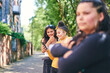 © Connect Images - Young woman with teenage sisters looking at smartphone by park