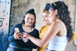© Connect Images - Young woman and her teenage sisters looking at smartphone in building entrance