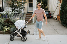 Father Pushing Baby Carriage On Pavement