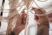 Close Up Of Person Working On Cream Coloured Macrame Curtain. 