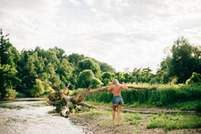 Rear View Of Young Woman Wearing Shorts Walking Along A River Bank.