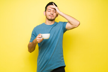 Wall Mural - Stressed man suffering from a headache and drinking coffee