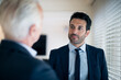 © Connect Images - Two businessmen standing indoors, talking.