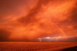 © Connect Images - A dust storm with vivid orange sky and rainbow, and cloud-to-ground lightning strike.