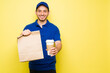© AntonioDiaz - Portrait of a delivery courier holding a brown bag and coffee