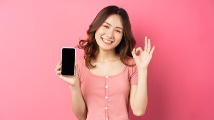 Wall Mural - Young asian girl using the phone on pink background