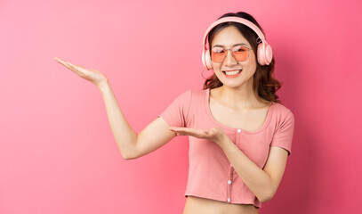 Wall Mural - Beautiful young girl wearing pink headphones on a pink background