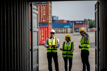 Team engineer dock control logistics worker wear safety helmets and protect suite open cargo container door and working and checking product with taplets.