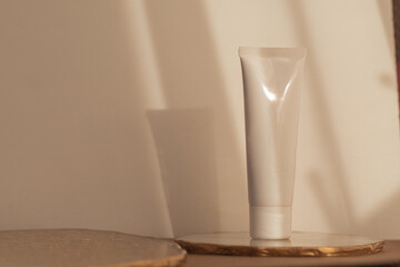 White cosmetic tube mockup on warm soft light background. Minimalism product still life. Light and shadow. Beauty blogging, skin care. Copy space
