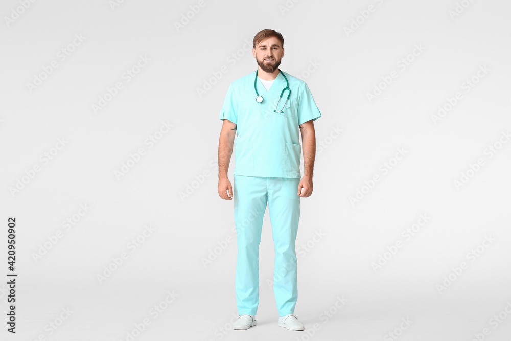 Young male doctor on light background