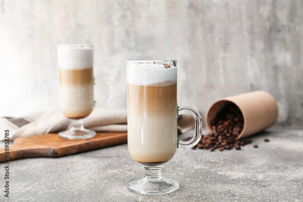 Glass cups of tasty latte on grey background