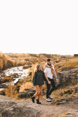 Happy in love romantic young cheerful couple man and woman married travel hiking walk together among the autumn forest and mountains looking for adventure enjoy the local nature, selective focus