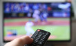 © Thomas - Baseball im Fernsehen schauen. Finger auf die Lauter-Taste auf der Fernbedienung. (Fokus auf der Fernbedienung)