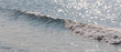 Petit rouleau de vague sur la mer en contre-jour et scintillement de l'eau, format bannière