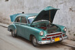 Havana. Cuba. A vintage car with its engine compartment open. The base of a person's head can be seen.  