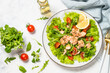 © nadianb - Green salad with baked fish at white table.