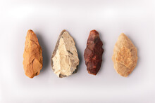 Four Prehistoric Quartzite Spearheads. From The Atherian Lithic Industry. From The Paleolithic And Acheulean Culture, From The Sahara Desert. On White Background