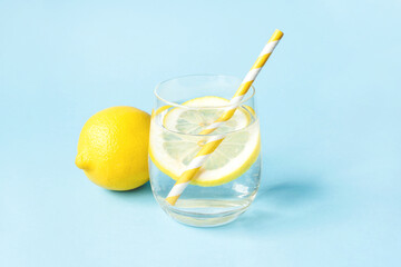 Wall Mural - Glass of water with lemon on a blue background. Summer refreshing drink.