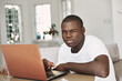 © SHOTPRIME STUDIO - guy of African appearance indoors with a laptop winks at the camera