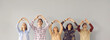 Group of happy grateful people looking up and doing symbolic heart shape hand sign gesture on gray background. Smiling young men and women promoting volunteering effort, sending love and thanking you
