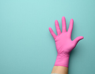 Wall Mural - female hand in a pink latex glove on a blue background, palm open