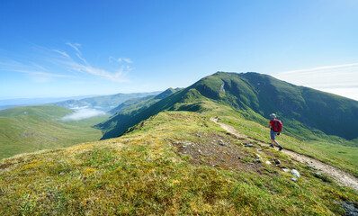 Wall Mural - A female hiker walking, hiking along a mountain path towards the summit of Ben Lawers from the top of Beinn Ghlas in the Scottish Highlands, UK landscape.