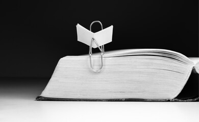 A paper clip sits on a book and reads