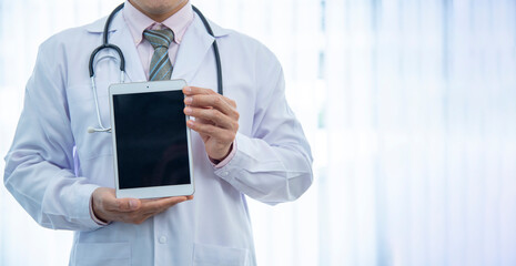 Medically, the doctor holds a white smartphone upside down, showing information about a blank smartphone with copyspace for a publicity ad on the background of a hospital examination room.