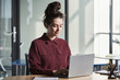 © AnnaStills - Young businesswoman sitting at her workplace and working online typing on laptop at office
