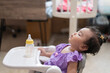Side view of cute little asian baby girl Sitting asleep on the dining table After eating full in the house