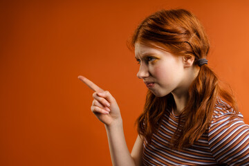 Wall Mural - Ginger displeased woman with tails looking and pointing finger aside