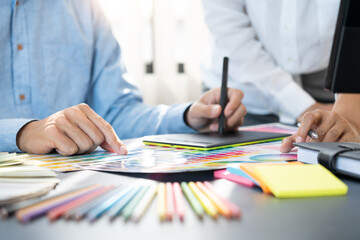 Poster - graphic designer team working on web design using color swatches editing artwork using tablet and a 