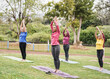 Multi generational women doing yoga exercise together outdoor at park with social distance for coronavirus outbreak - Multiracial people having fun doing sport together