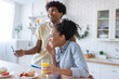 © LIGHTFIELD STUDIOS - Laughing african american couple using smartphone during breakfast