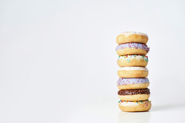 Best dessert recipe. Tower of various sweet colorful donuts with sprinkles and glaze isolated over light background, copy space for text