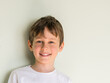 © Sergey + Marina - Portrait of smiling 8 year old boy wearing white t-shirt against gray wall with copy space