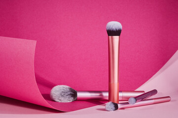 Wall Mural - Makeup brushes on pink and burgundy paper background. Cosmetic professional Make up Brushes