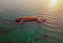 The Old Rusty Ship Was Stranded By A Storm. Oil Spill From A Tanker, Environmental Pollution. Ship At Sunrise