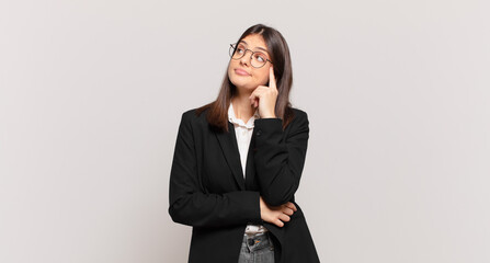 young business woman with a concentrated look, wondering with a doubtful expression, looking up and to the side