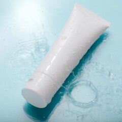 white cosmetic product in tube on color blue background with water drops. mock up skincare cosmetic 
