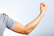 a woman is showing her fist and muscles of her forearm and arm in contraction as a gesture and demonstration of strength. She uses her other hand to roll back the sleeve. Concept for girl power.