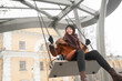 © Вадим Каштанов - Young woman in warm clothes rides on swing in playground.
