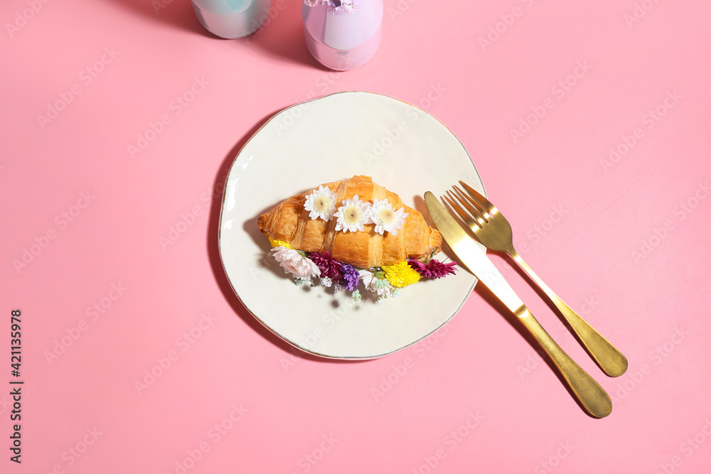 Composition with tasty croissant and flowers on color background