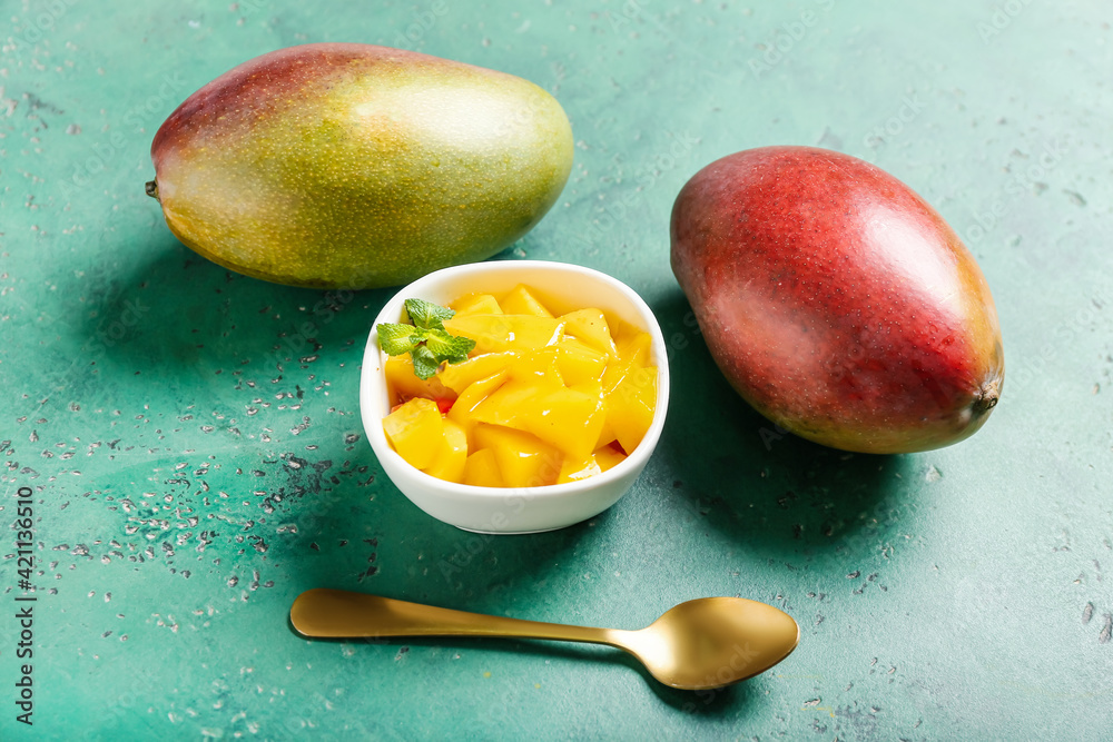 Bowl with tasty mango salad and sauce on color background