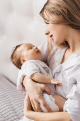 A loving mother carries her newborn baby at home. portrait of a happy mother holding a sleeping baby in her arms. Mother hugs her little 4-month-old daughter