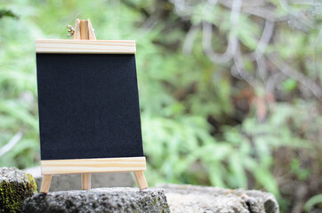 empty standing chalk board on garden. blank black board with blurred background for text, menu and sign