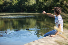 Young Happy Man Feeding Ducks In The Pond